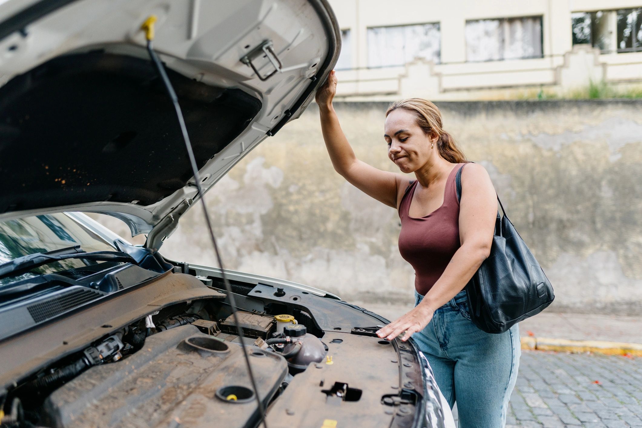 Woman holding car hood open outdoors Woman holding car hood open outdoors